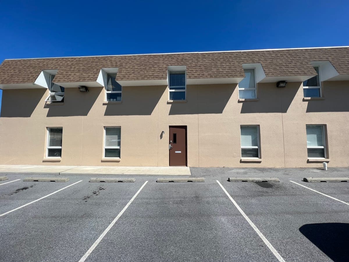 Full front of the finished stucco commercial building with awnings and a brown entry door
