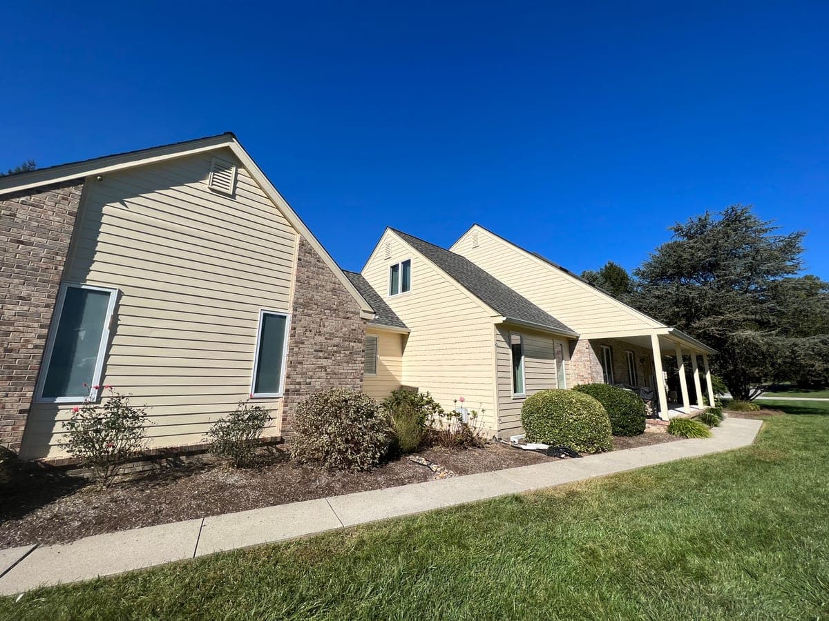 Finished cream ranch side elevation with brick, white trim and covered walk