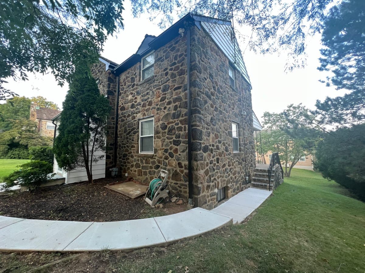 Rear of a fieldstone house with fresh white trim and new concrete walk