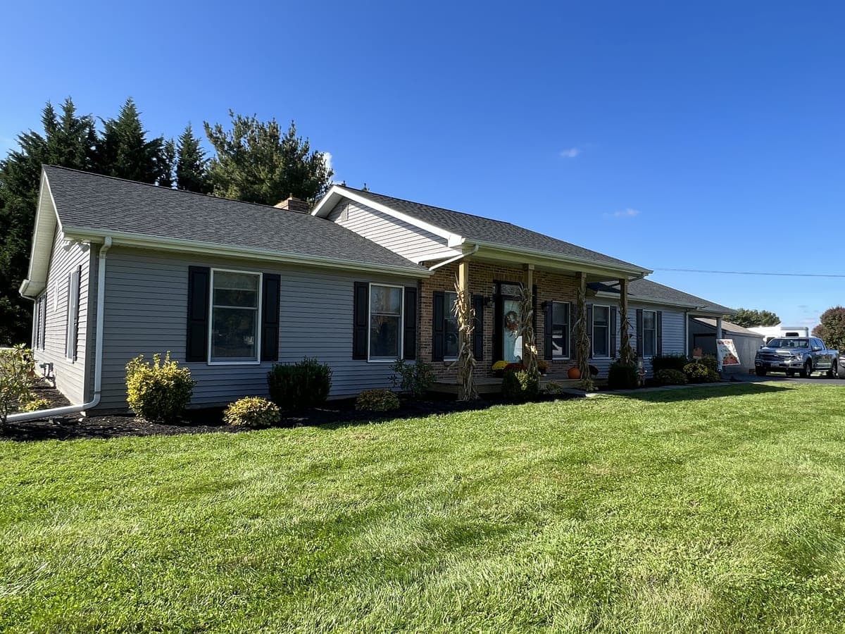 Gray ranch with black shutters, brick entry columns and fall planting at the porch
