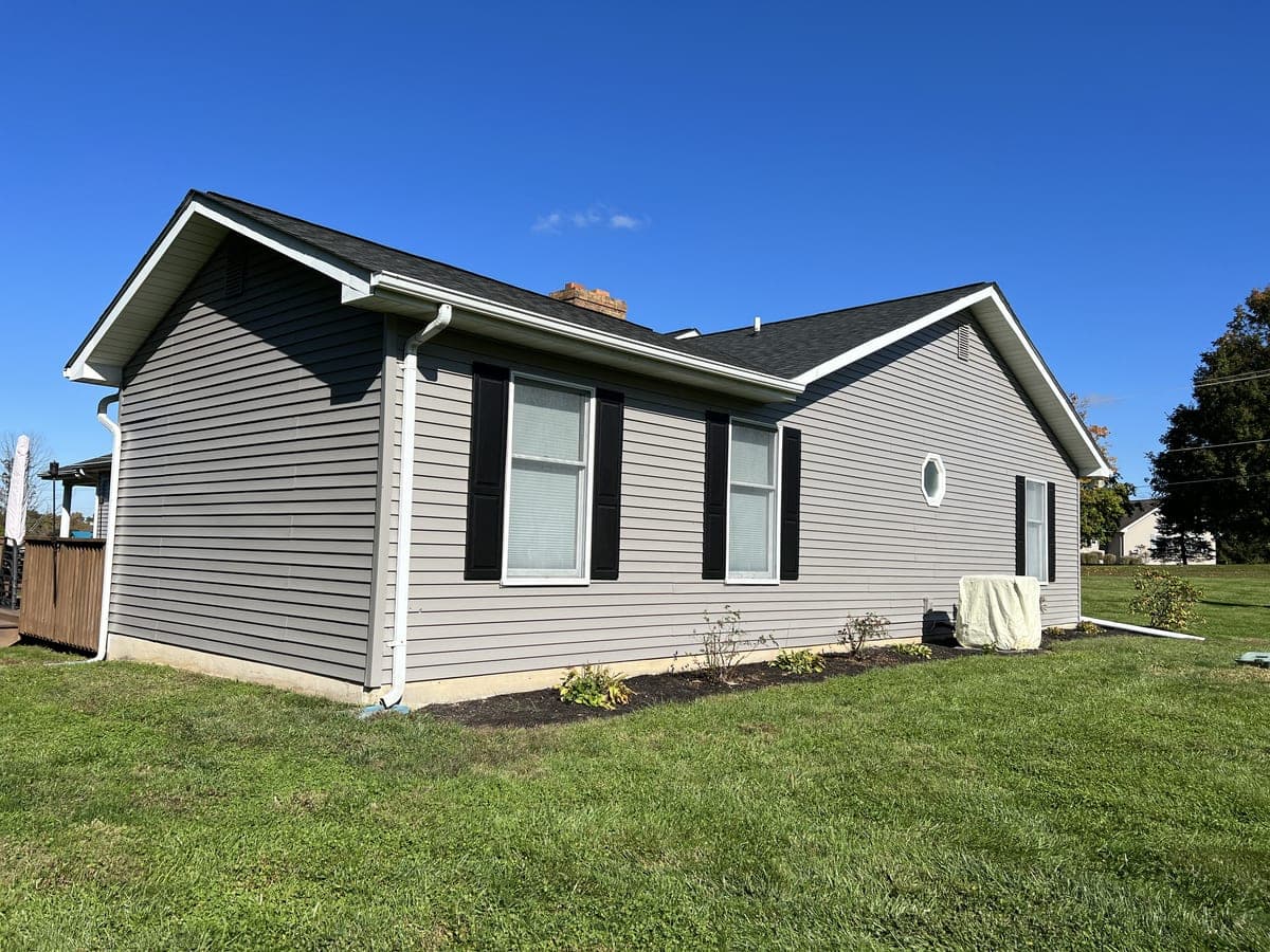 Side and rear of the gray ranch with black shutters, white trim and downspouts