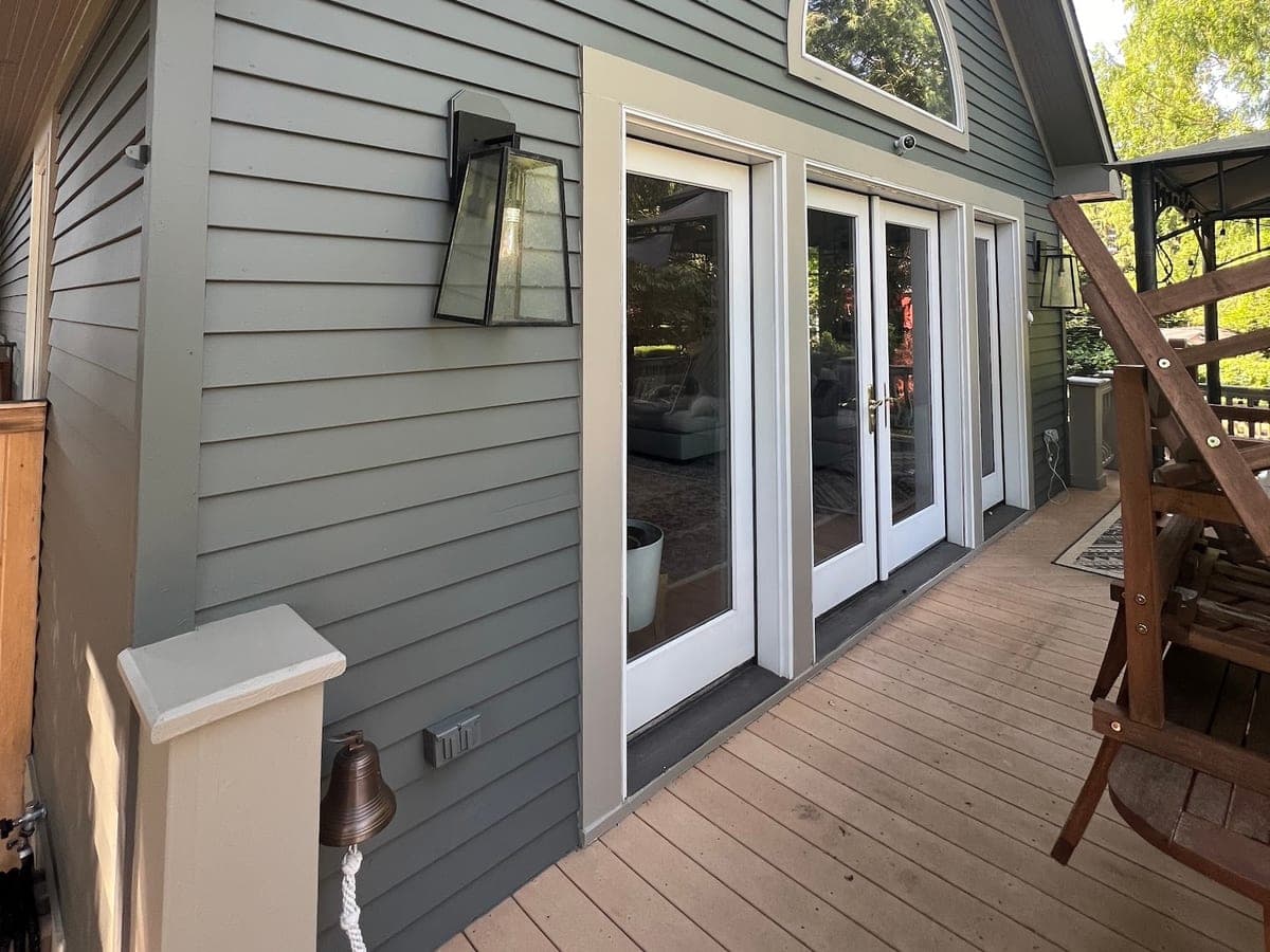 Gray lap-sided rear elevation with white trim, arched transom window and composite deck
