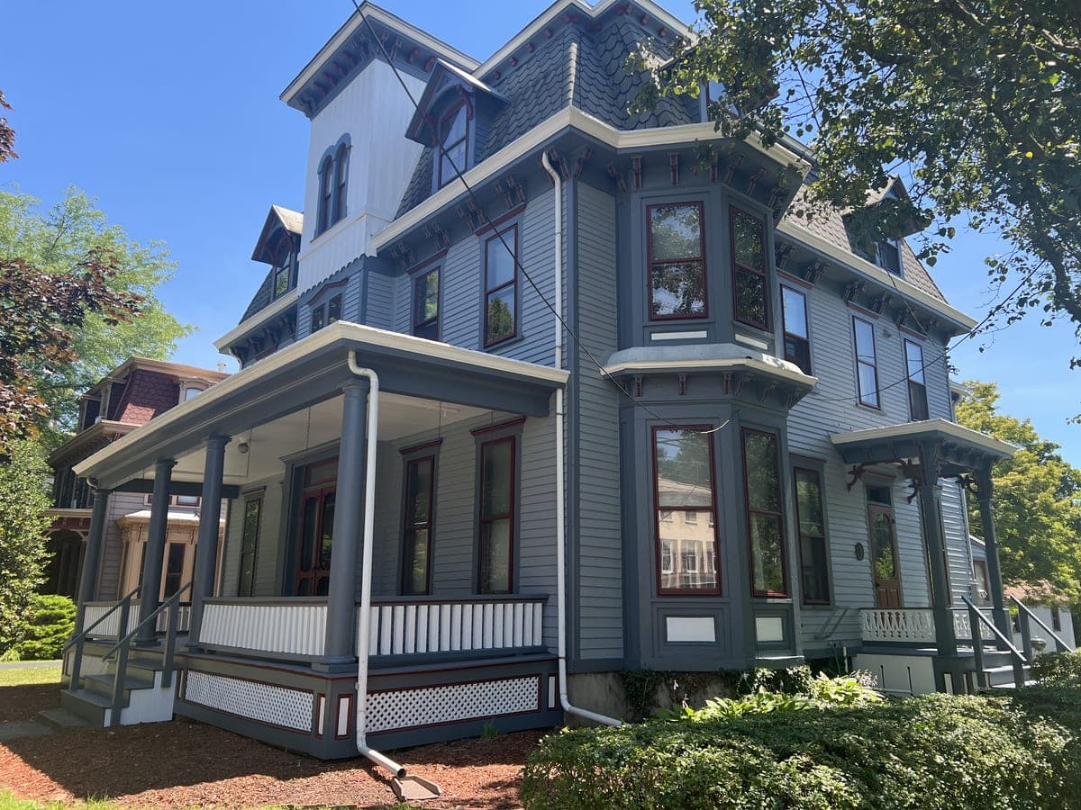 Finished gray Victorian three-quarter view with wraparound porch and lattice skirting