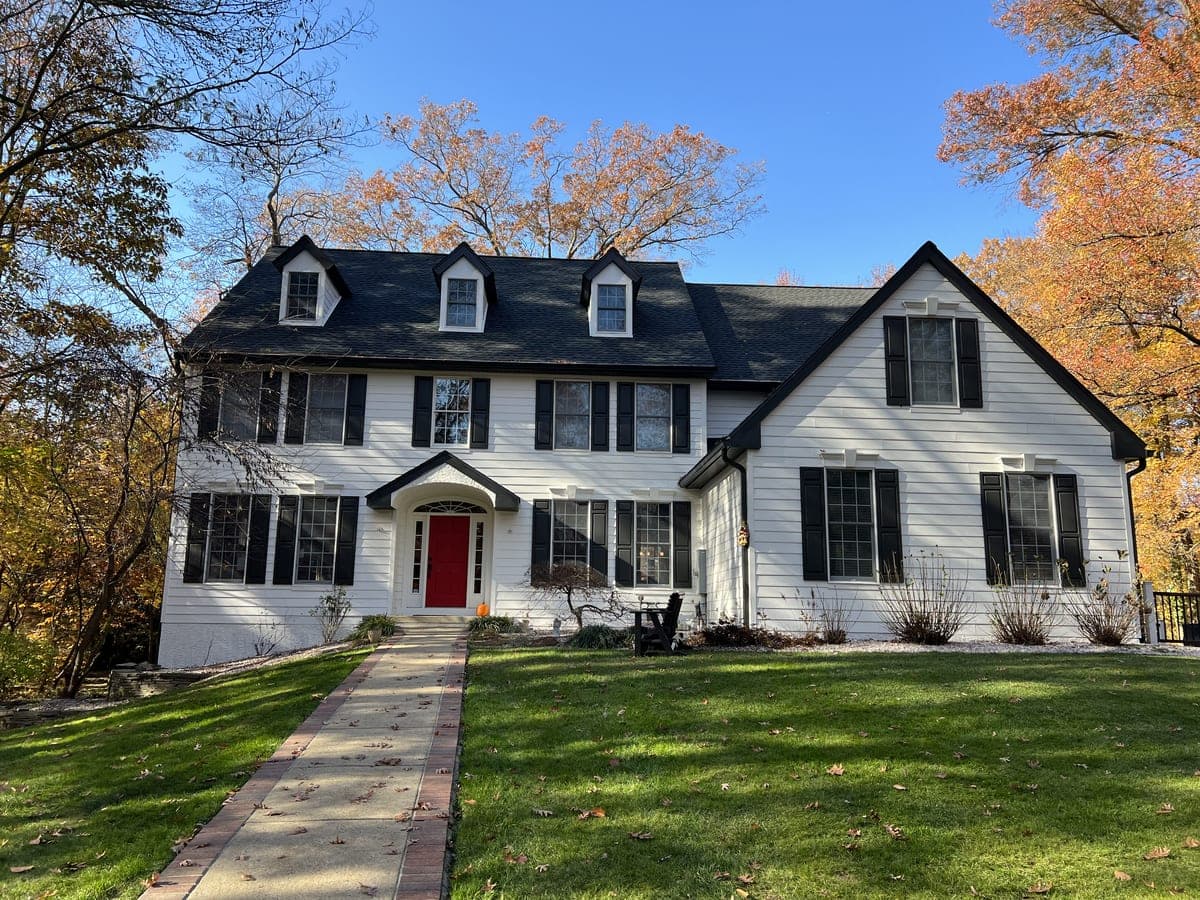 Third view of the white colonial, wider frame with driveway and side wing