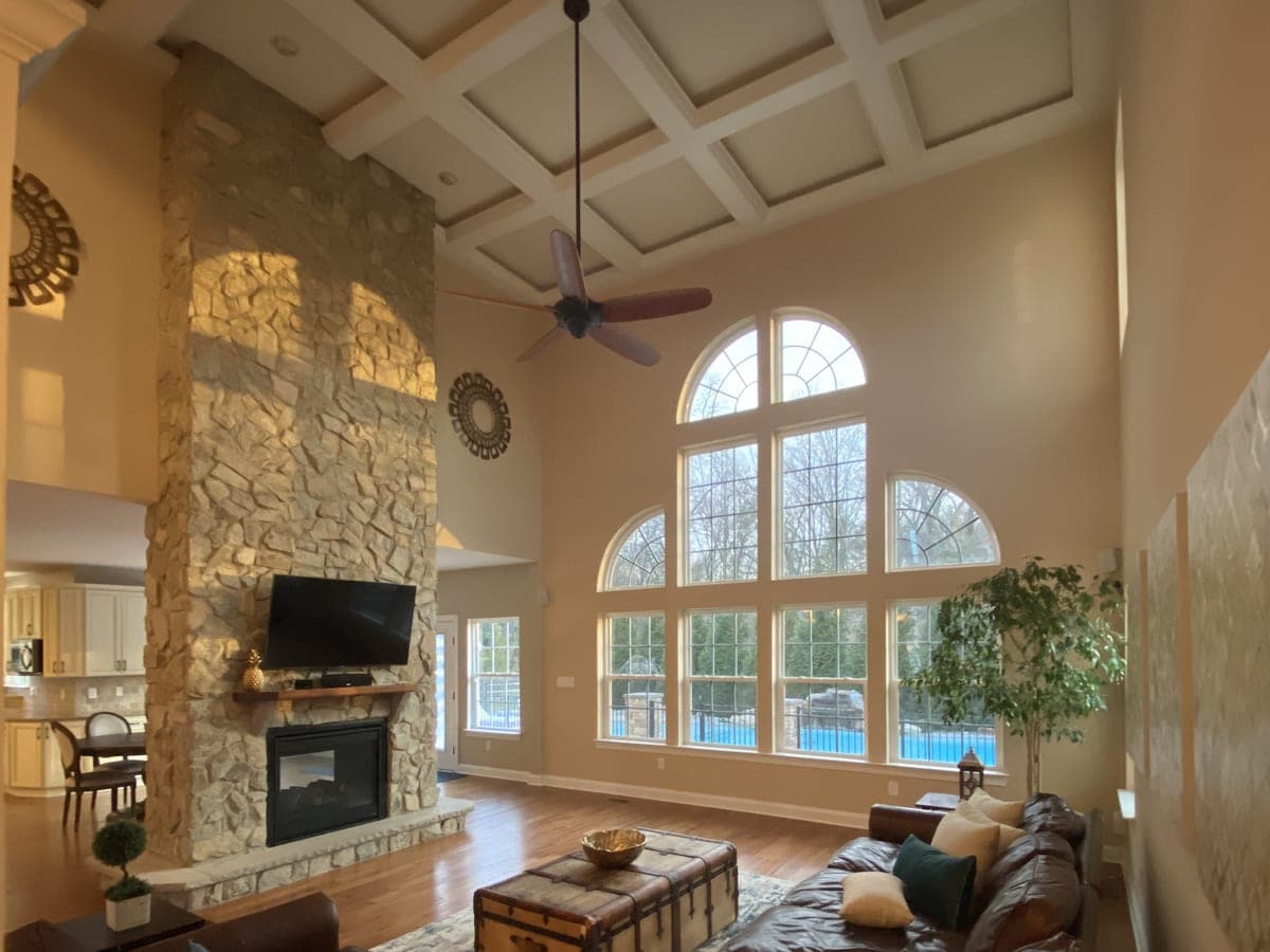Two-story great room with coffered ceiling, stone fireplace, arched window wall