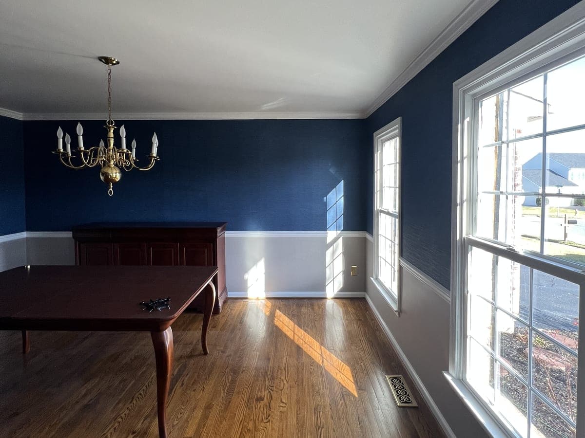 Dining room with navy upper wall, white chair rail and wainscot, brass chandelier