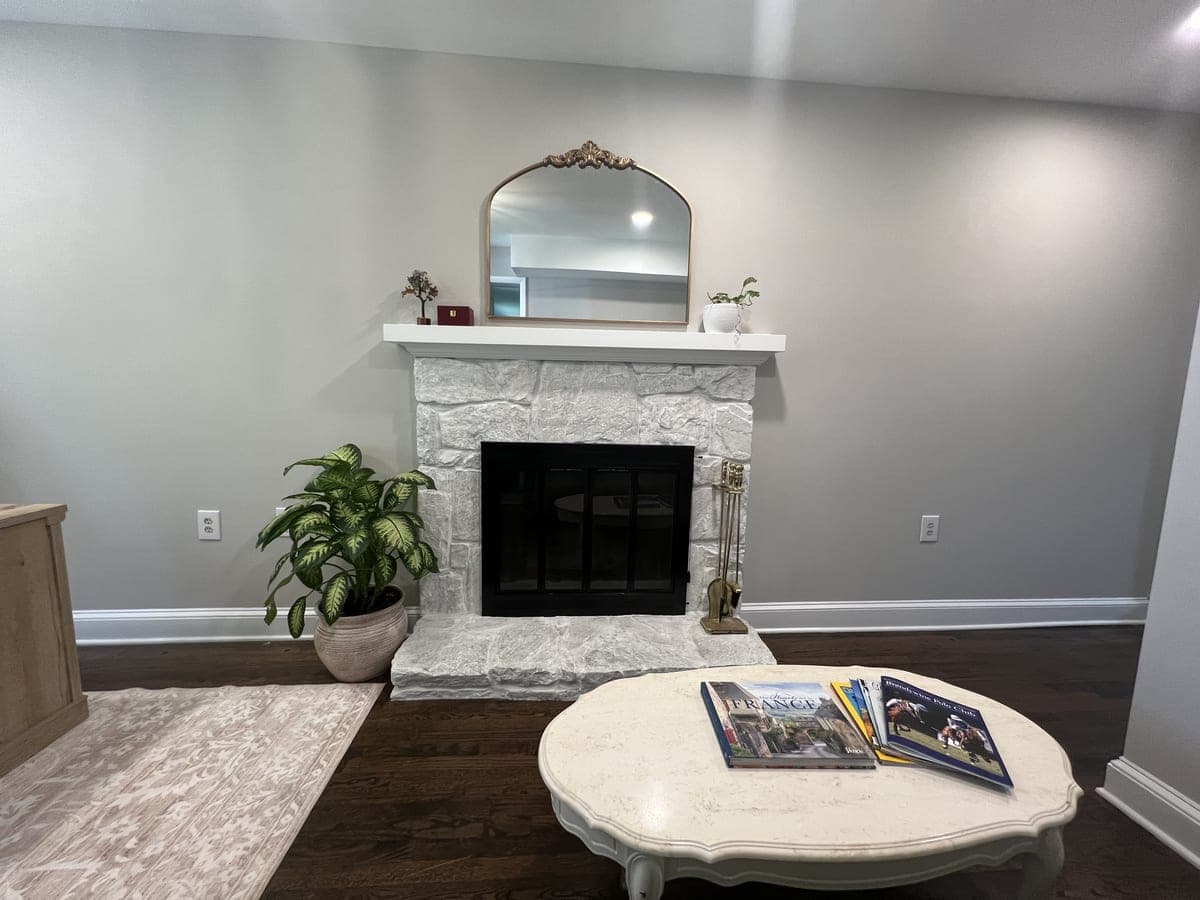 Living room with pale gray walls, white stone fireplace and mantel, dark hardwood floor