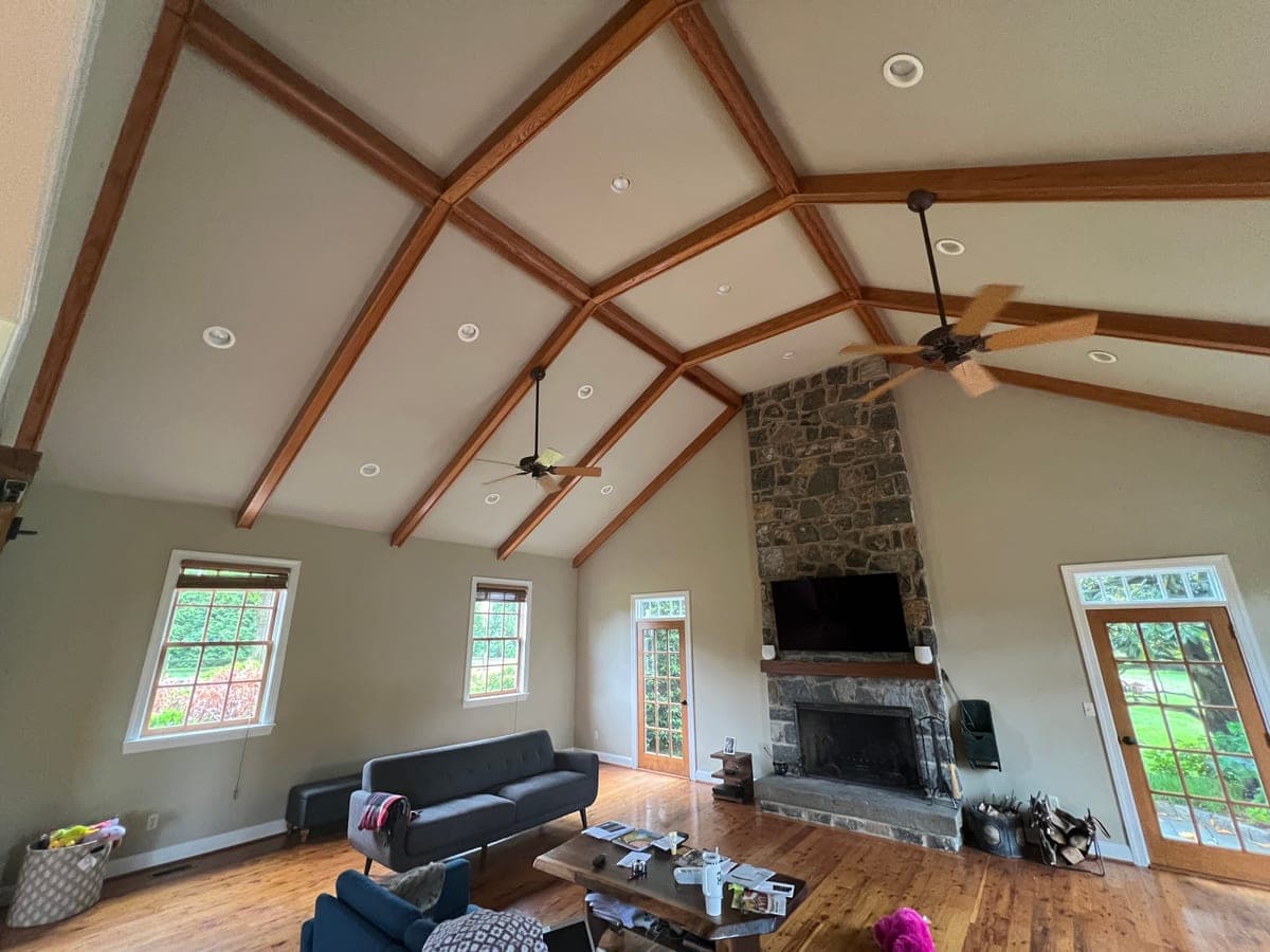 Vaulted great room with exposed timber trusses, stone fireplace and sage walls