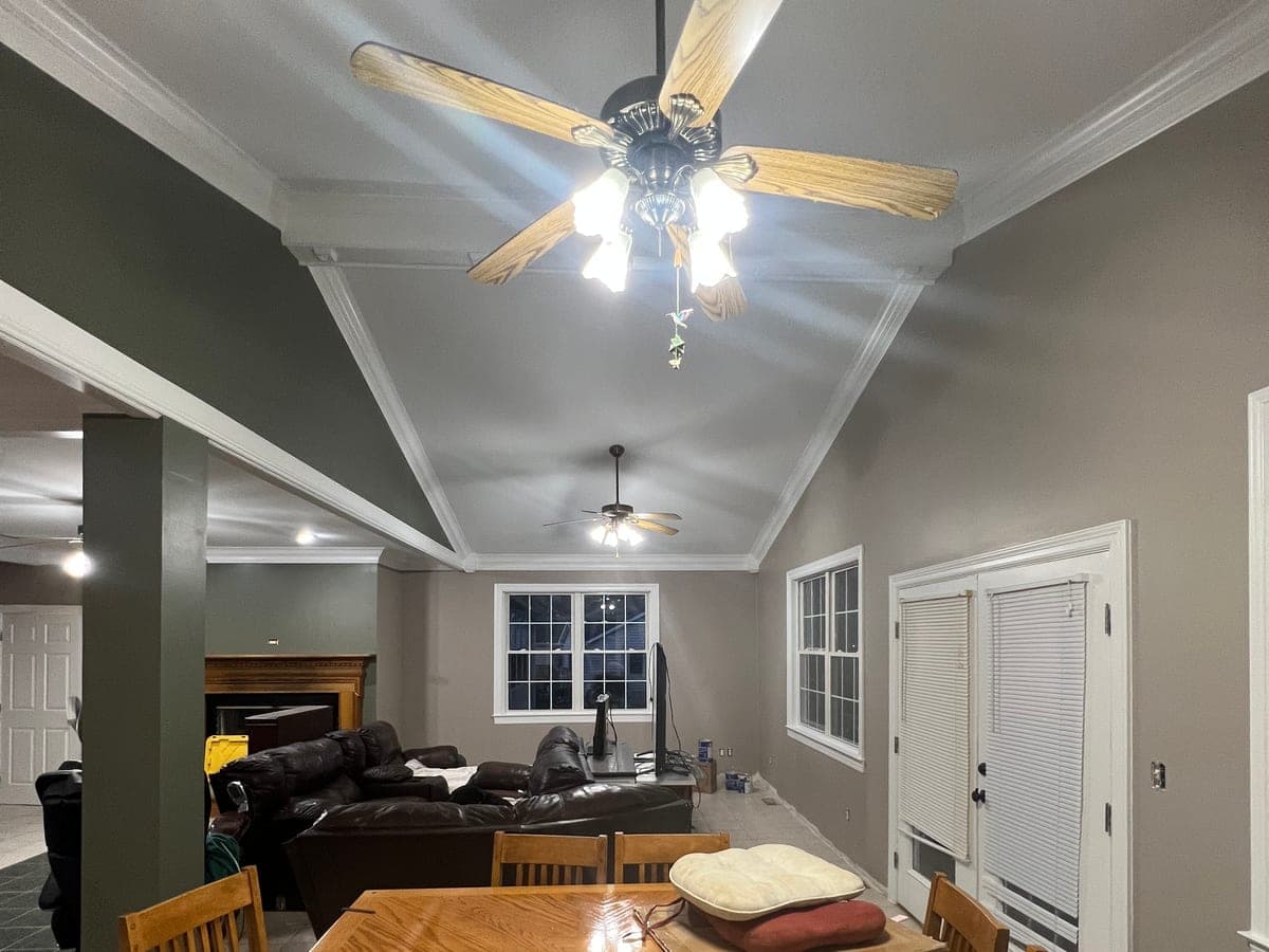 Vaulted dining and living area, sage-gray walls, white ceiling and ceiling fans