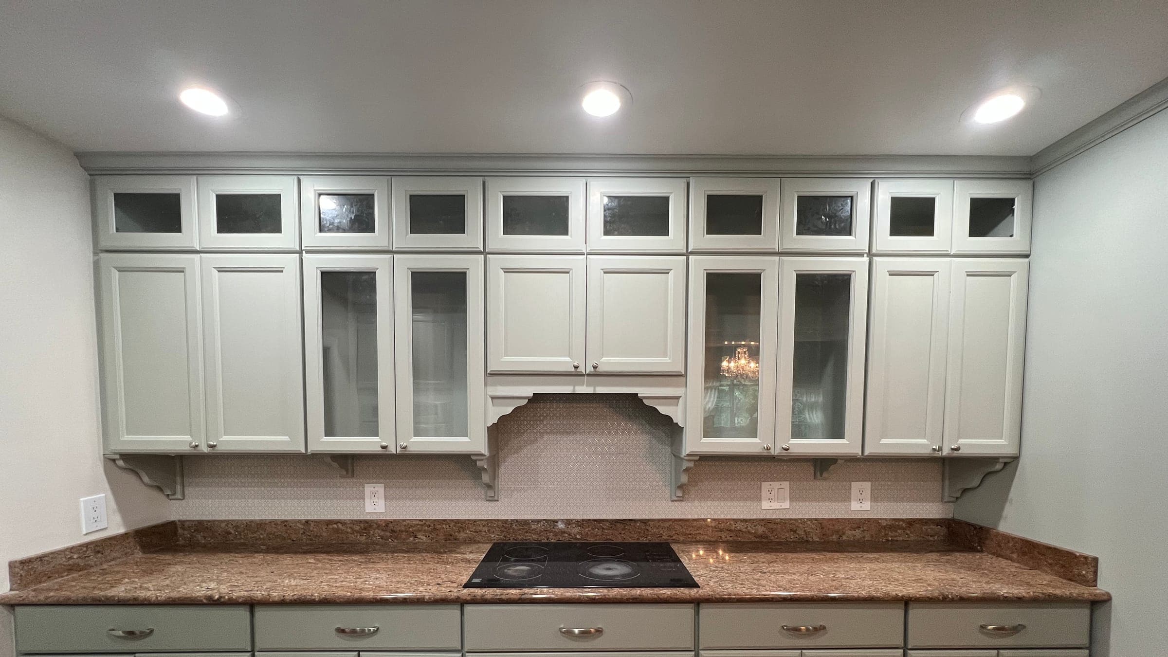 Kitchen cabinets painted sage green, with glass-front uppers and a granite counter