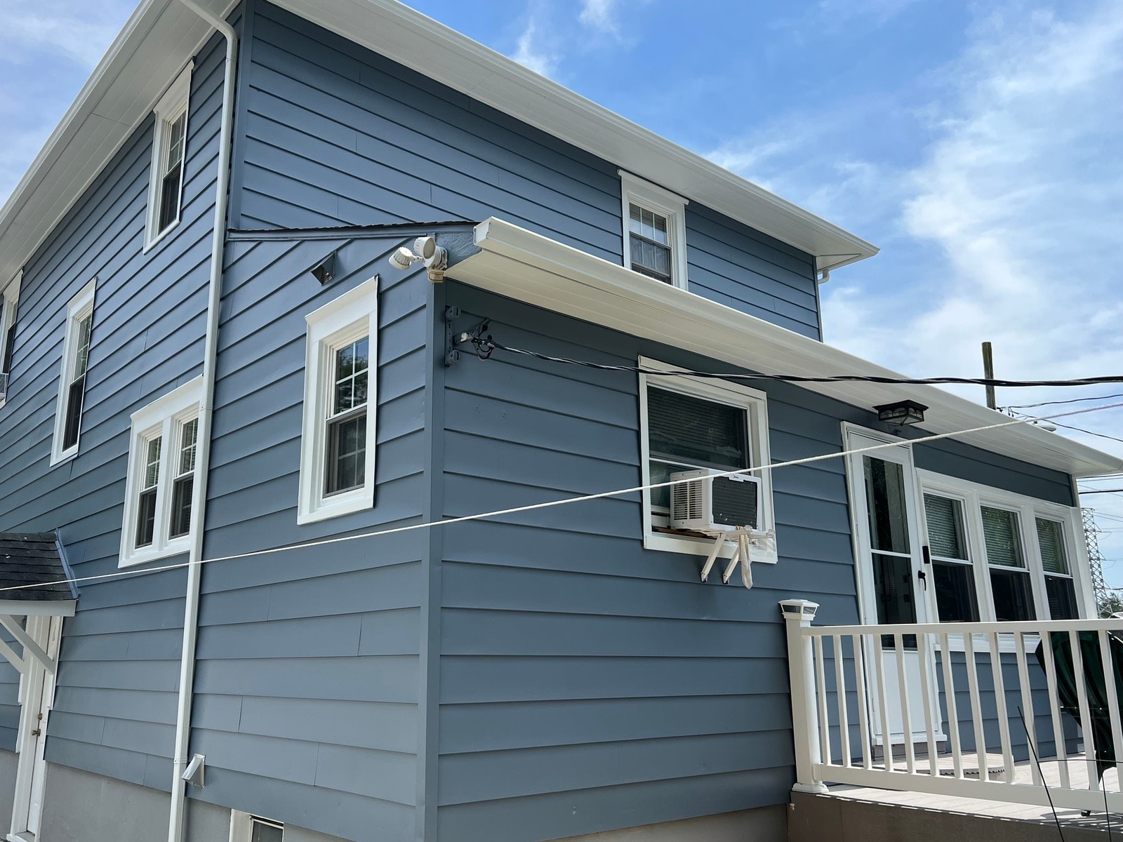 The same corner of the house finished in slate blue siding with white trim and gutters