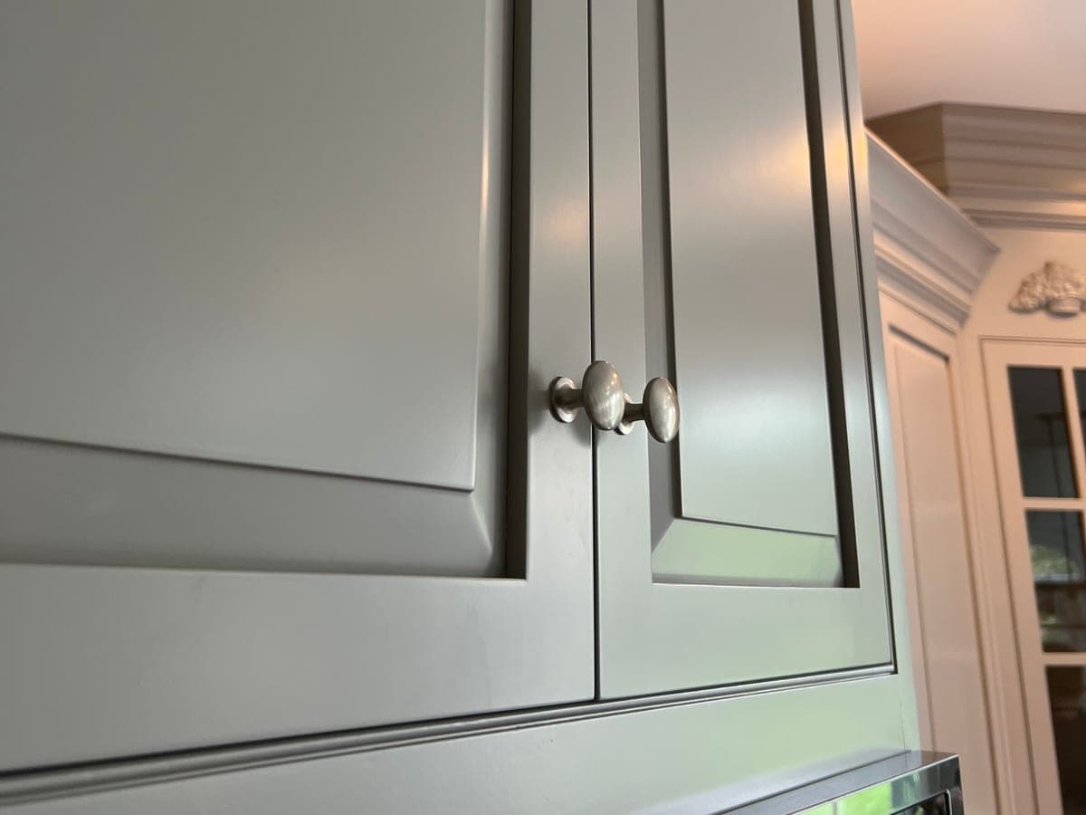 Close view of a finished sage-green painted cabinet door and crown detail