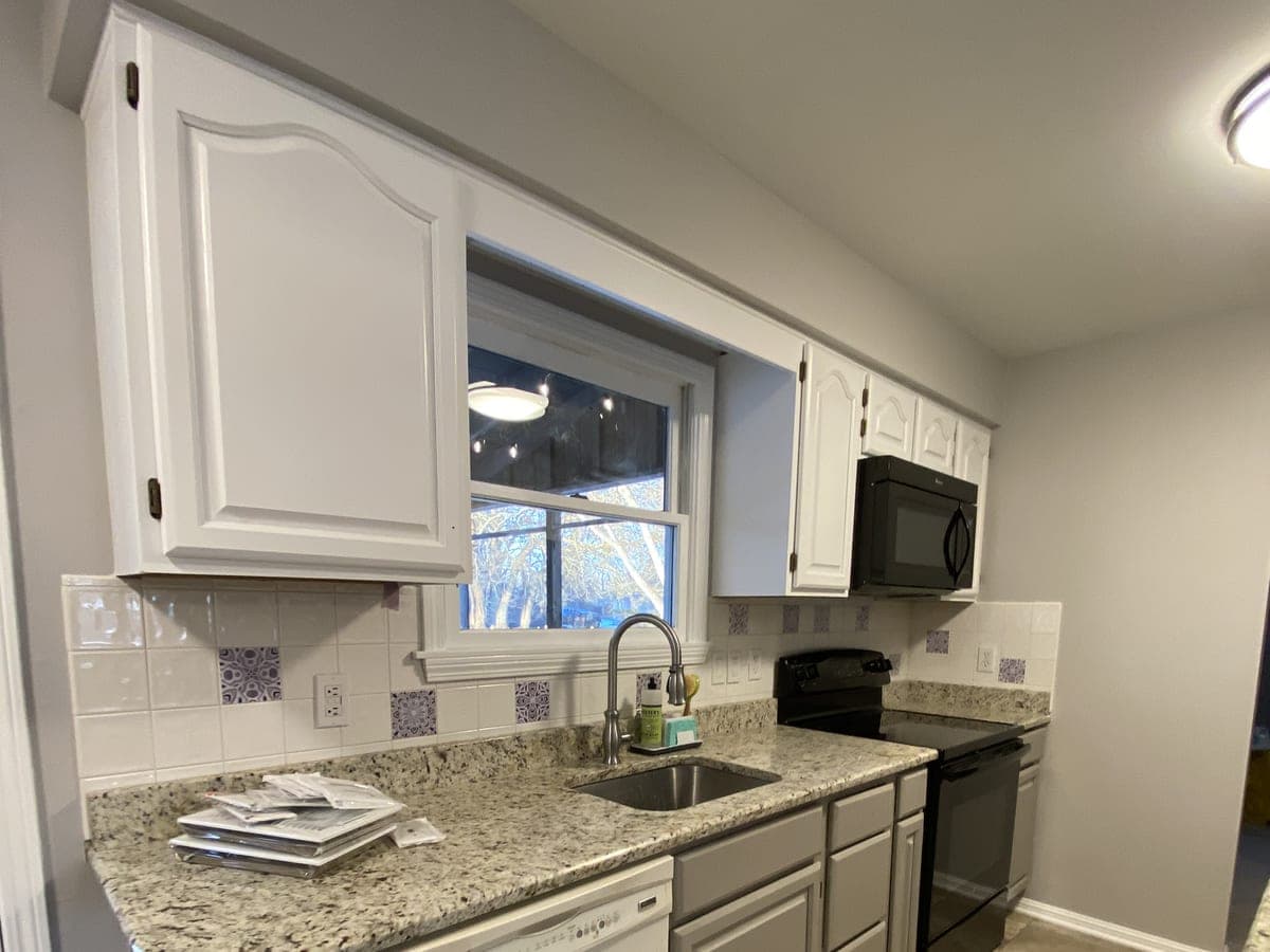 Finished galley kitchen: white uppers, gray lowers, granite counters, tile backsplash and floor