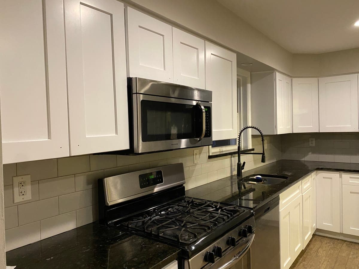 Finished white shaker kitchen with dark granite, subway backsplash and stainless range