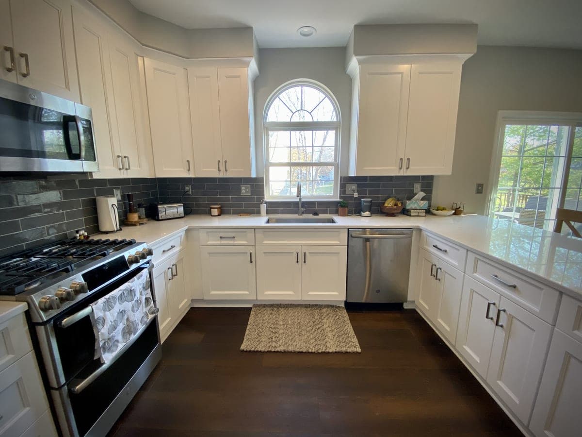 White shaker kitchen with gray subway backsplash, quartz tops and stainless appliances
