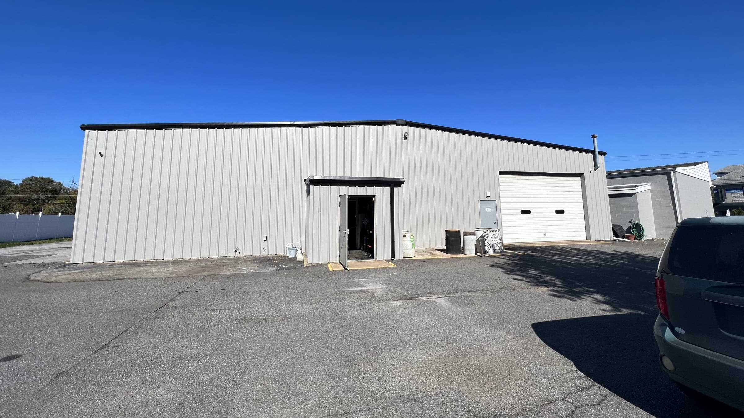 Long white metal building elevation with black trim, entry door and overhead door