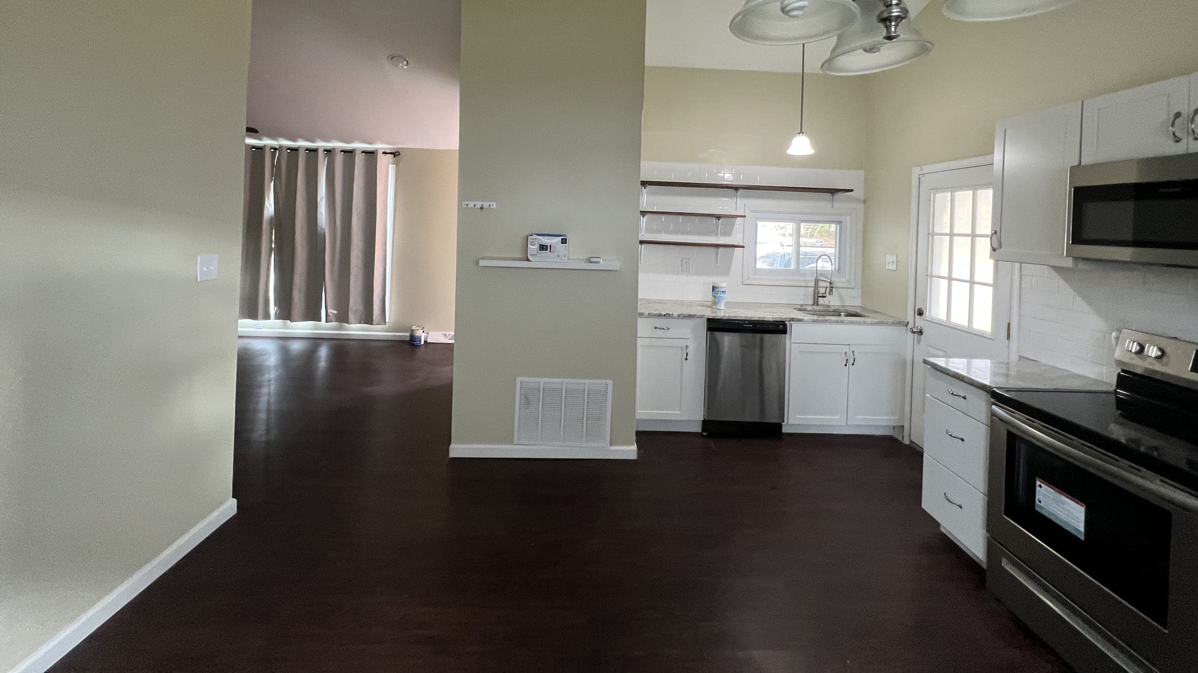 Open sage kitchen and living area in a new build with white cabinets and dark floor